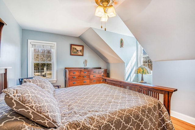 bedroom with baseboards, lofted ceiling, wood finished floors, and a ceiling fan