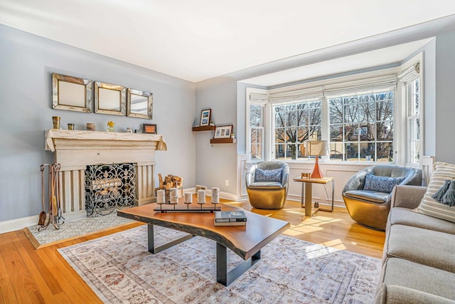 living area with a fireplace with flush hearth, baseboards, and wood finished floors