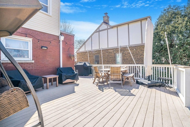 deck with outdoor dining space and a grill