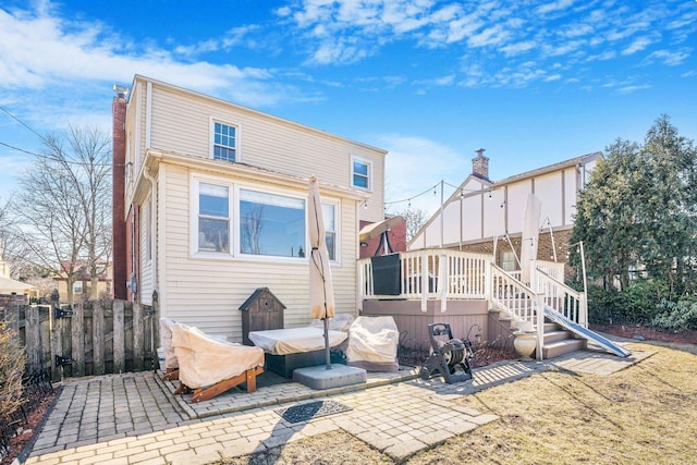 back of house featuring a patio area, a deck, a chimney, and fence