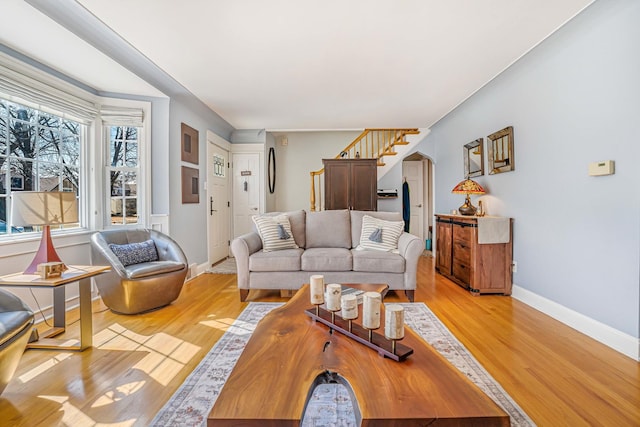 living area featuring light wood finished floors, stairway, and baseboards