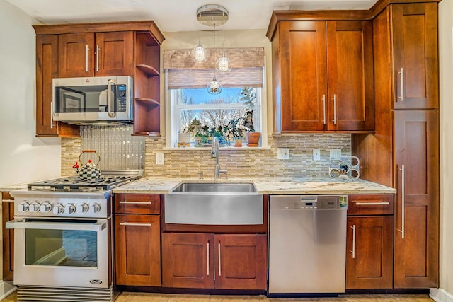 kitchen featuring light stone counters, a sink, appliances with stainless steel finishes, decorative light fixtures, and backsplash