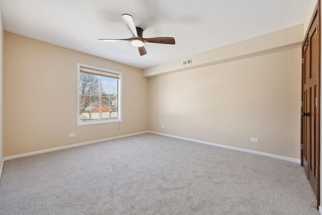 spare room featuring light colored carpet, ceiling fan, visible vents, and baseboards