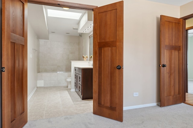 full bathroom with a skylight, vanity, and baseboards