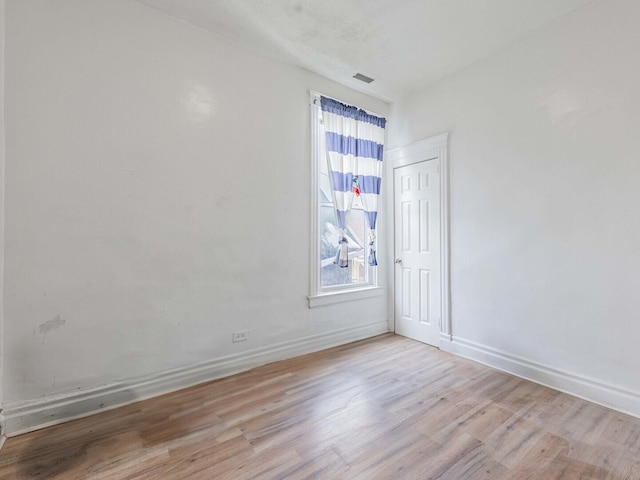 unfurnished room with light wood-type flooring, visible vents, and baseboards