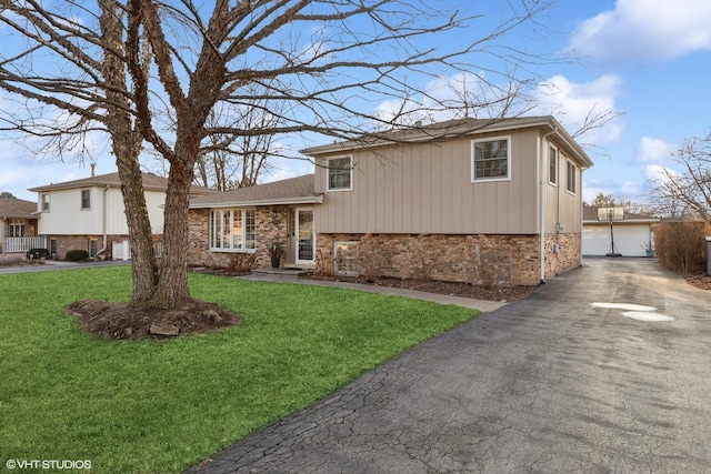 tri-level home featuring an outbuilding, brick siding, a detached garage, and a front lawn