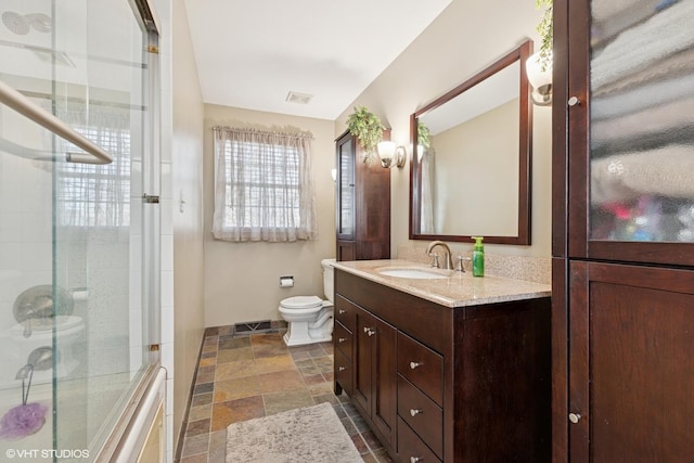 bathroom with toilet, stone tile floors, visible vents, vanity, and an enclosed shower