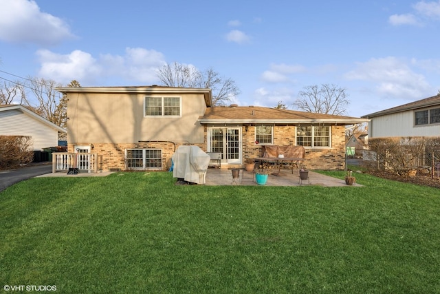 rear view of house with a yard, a patio, brick siding, and stucco siding