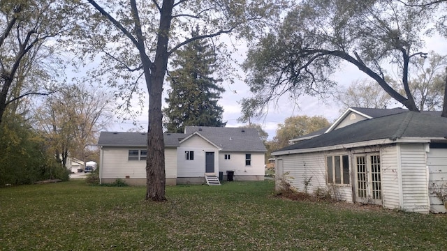 rear view of property featuring entry steps and a yard