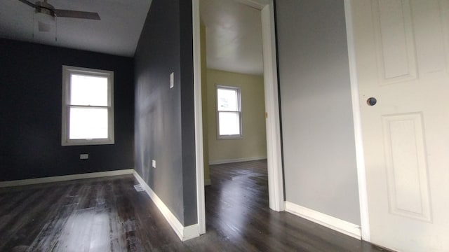 interior space featuring a ceiling fan, dark wood finished floors, and baseboards