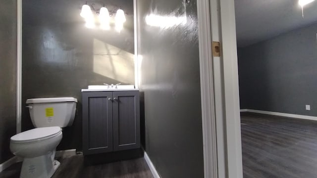 bathroom featuring toilet, baseboards, wood finished floors, and vanity