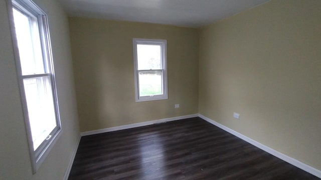 unfurnished room featuring dark wood-type flooring and baseboards