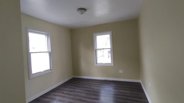 spare room featuring dark wood-style flooring and baseboards