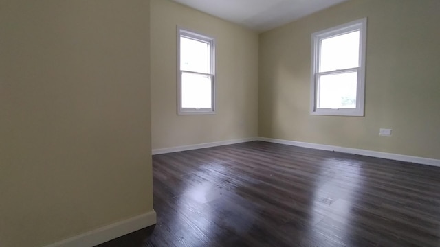 spare room with plenty of natural light, baseboards, and dark wood finished floors