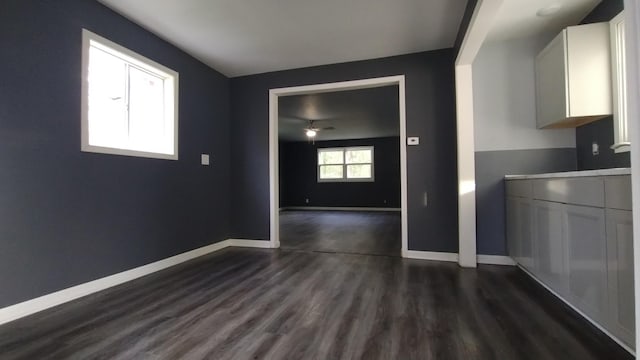 unfurnished dining area with dark wood-type flooring and baseboards