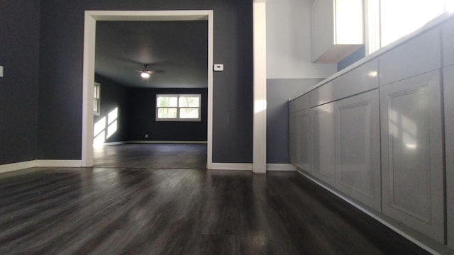 spare room featuring dark wood-style flooring, a ceiling fan, and baseboards