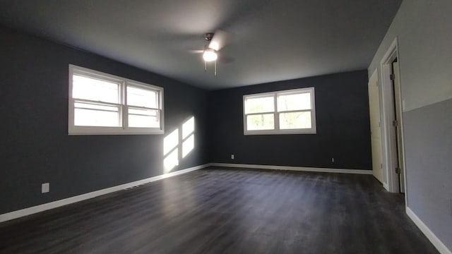 unfurnished room featuring baseboards, dark wood finished floors, and a ceiling fan