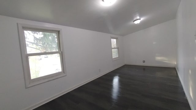 spare room with dark wood-style floors, lofted ceiling, and baseboards