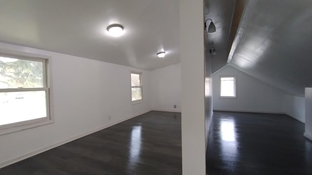 bonus room with dark wood-style floors, baseboards, and vaulted ceiling