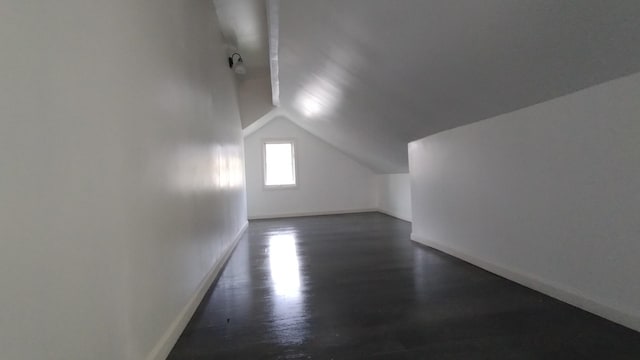 bonus room with lofted ceiling, dark wood-style flooring, and baseboards