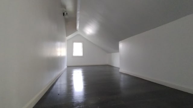 additional living space featuring lofted ceiling, baseboards, and dark wood-style flooring