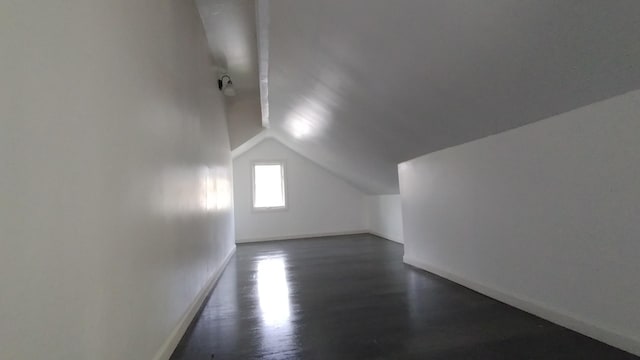 additional living space featuring baseboards, vaulted ceiling, and dark wood-style flooring