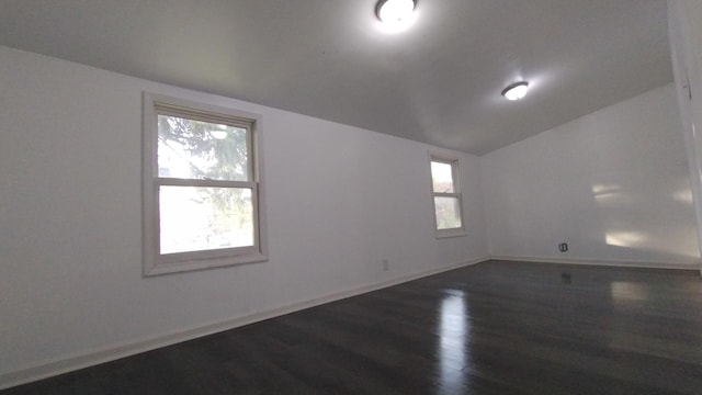 empty room with vaulted ceiling, dark wood-style floors, and baseboards