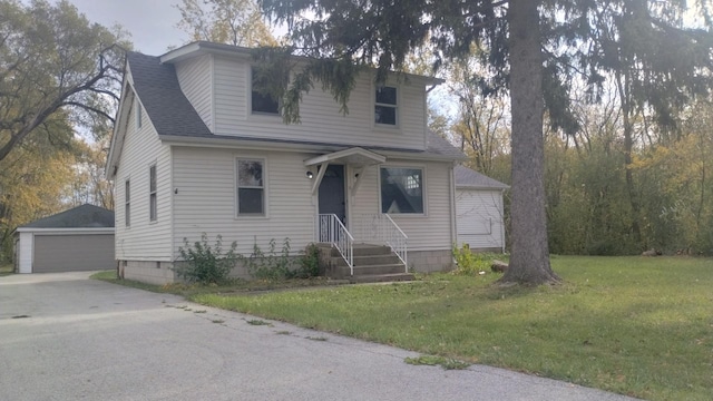 view of front of property with an outbuilding, a front lawn, roof with shingles, and a detached garage