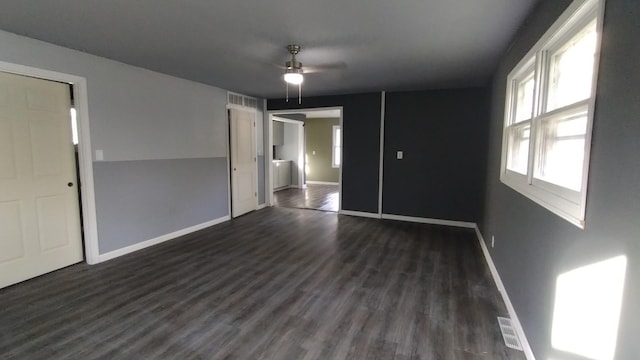 spare room with a ceiling fan, dark wood-style flooring, visible vents, and baseboards