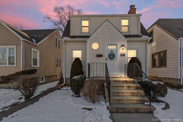 view of front of property featuring a shingled roof and a chimney