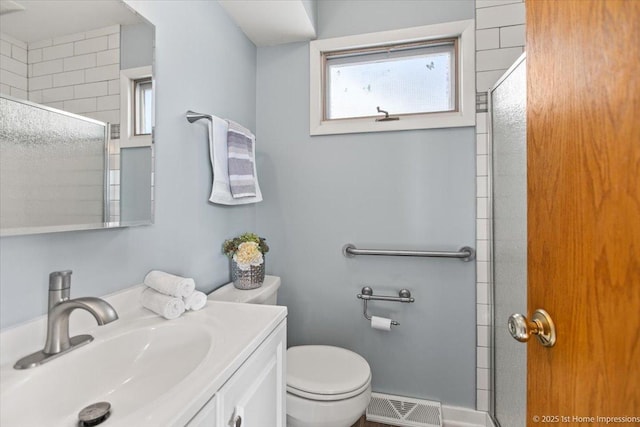 bathroom featuring visible vents, a tile shower, vanity, and toilet