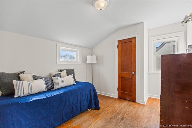 bedroom with vaulted ceiling, light wood finished floors, and baseboards