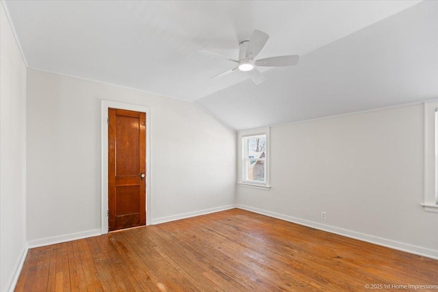 spare room featuring a ceiling fan, wood-type flooring, vaulted ceiling, and baseboards