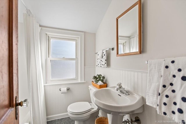 bathroom with a wainscoted wall, lofted ceiling, and toilet