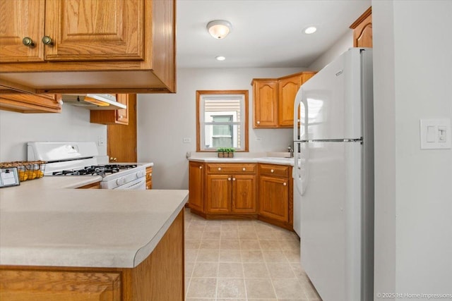 kitchen featuring white appliances, brown cabinetry, a peninsula, light countertops, and recessed lighting