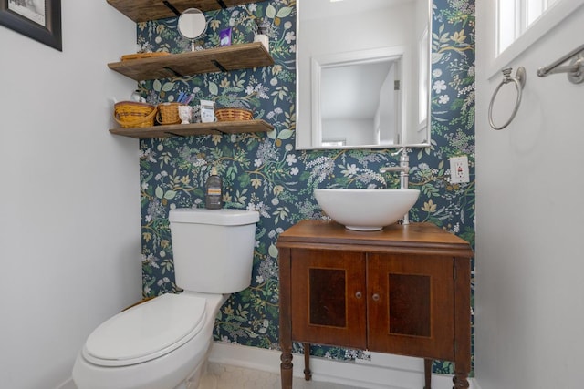 bathroom with baseboards, vanity, toilet, and wallpapered walls