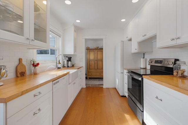 kitchen with a sink, electric range, butcher block countertops, and dishwasher