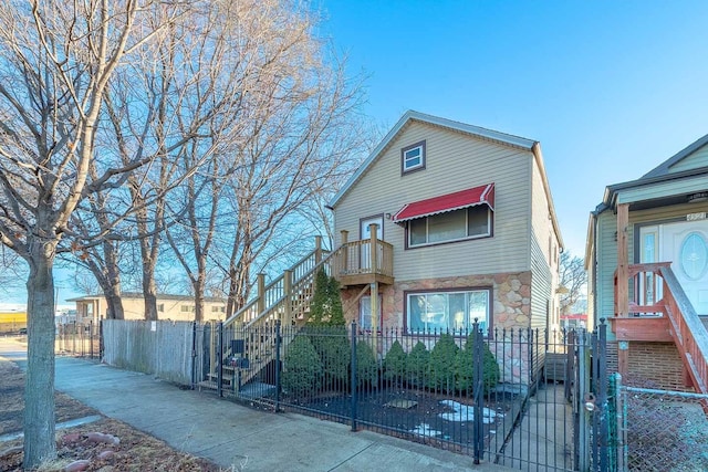 view of front of property featuring stone siding, a fenced front yard, and a gate