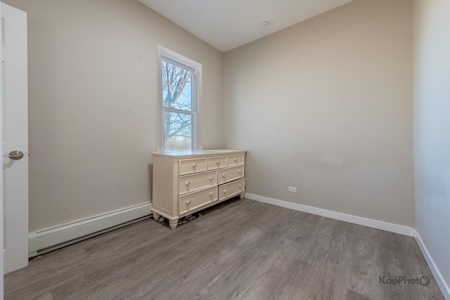 unfurnished bedroom with baseboards, baseboard heating, and wood finished floors