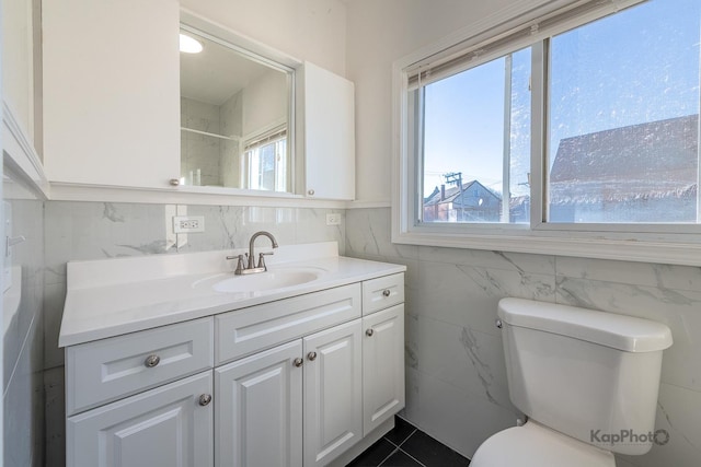 bathroom featuring tile patterned floors, vanity, toilet, and tile walls