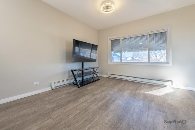 spare room with a baseboard radiator, baseboards, and wood finished floors