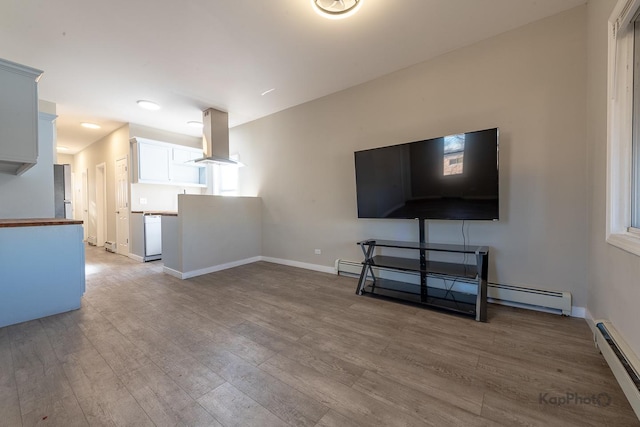 unfurnished living room featuring a baseboard heating unit, baseboards, baseboard heating, and wood finished floors