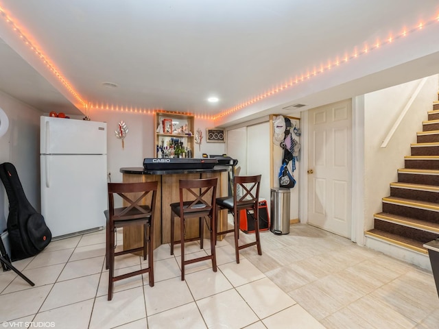 kitchen with light tile patterned flooring and freestanding refrigerator