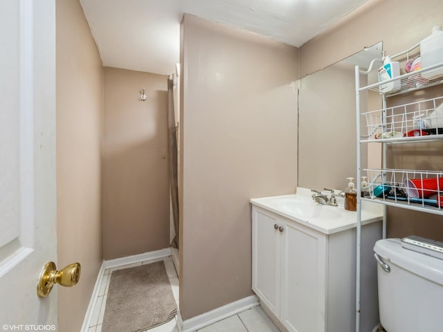 bathroom with baseboards, vanity, toilet, and tile patterned floors