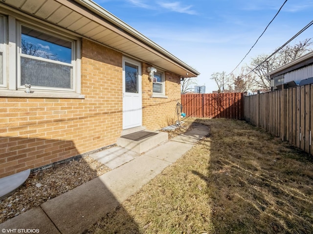 property entrance featuring fence and brick siding