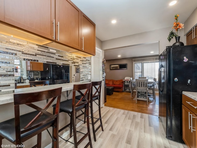 kitchen featuring light wood-style flooring, freestanding refrigerator, and brown cabinets