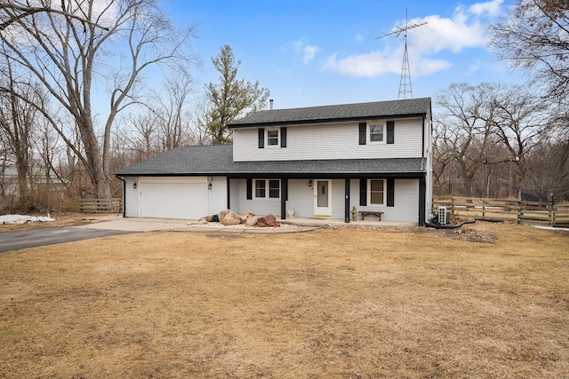 traditional-style home featuring driveway, a garage, covered porch, fence, and a front yard