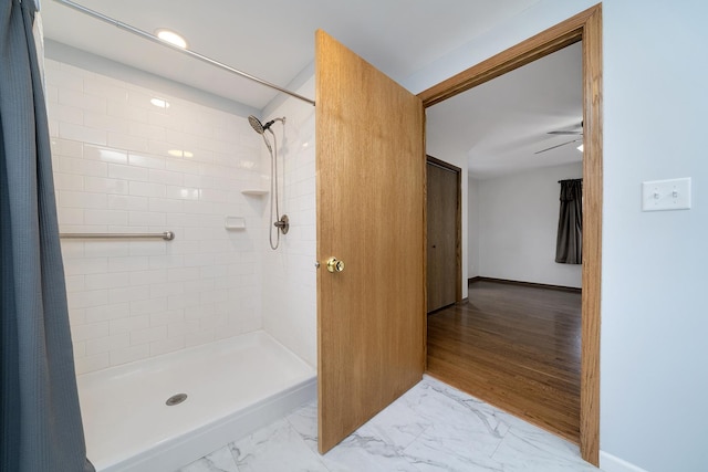 bathroom featuring marble finish floor, tiled shower, and baseboards