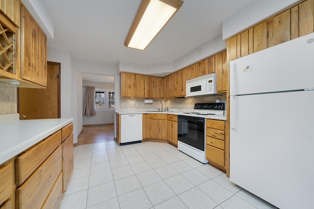 kitchen with light countertops, white appliances, backsplash, and a sink