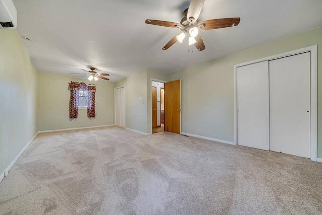 unfurnished bedroom with carpet floors, ceiling fan, baseboards, and multiple closets